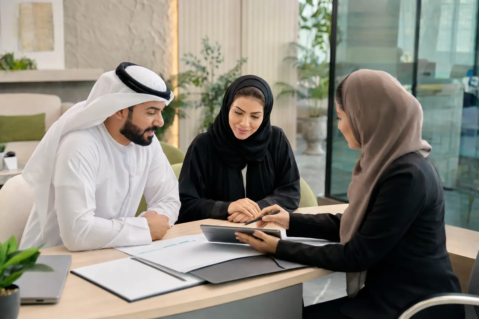 عميلان إماراتيان يراجعان معاملة مع موظفة دعم في مكتب حديث