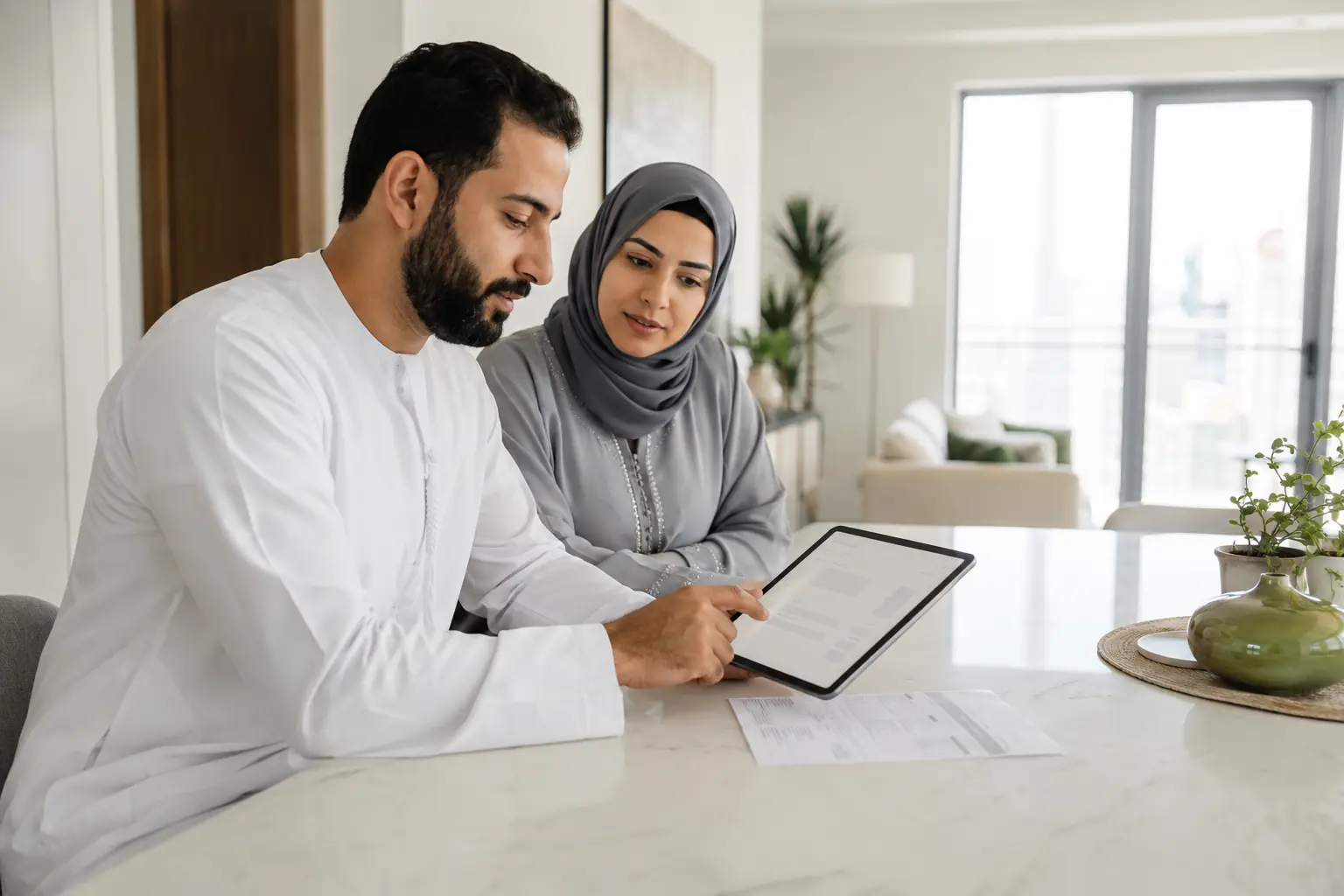 مقيمان إماراتيان يراجعان حساب مرافق على جهاز لوحي في المنزل
